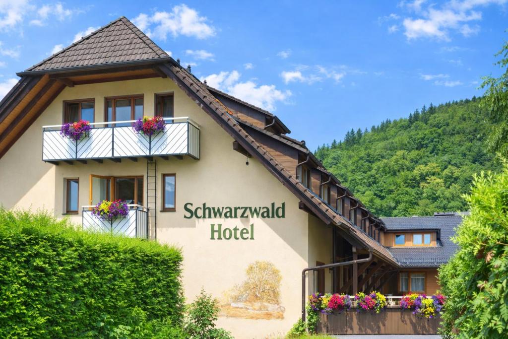 a house in the mountains with a sign for the hotel at Hotel Grünwinkel in Oberharmersbach