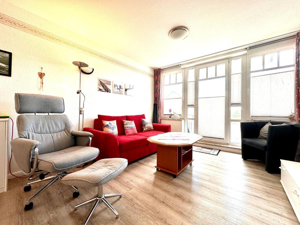 a living room with a red couch and a chair at Ferienwohnung De Kiewitt 207 in Dorum-Neufeld