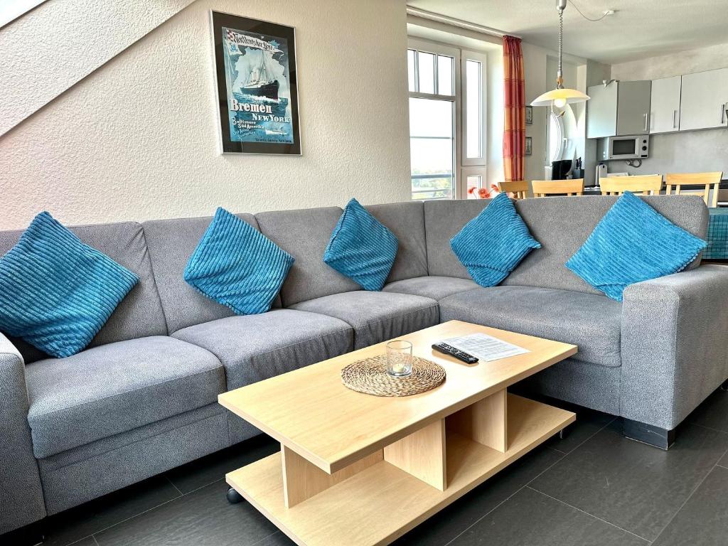 a living room with a gray couch with blue pillows at Ferienwohnung Suite de Svaan in Dorum-Neufeld