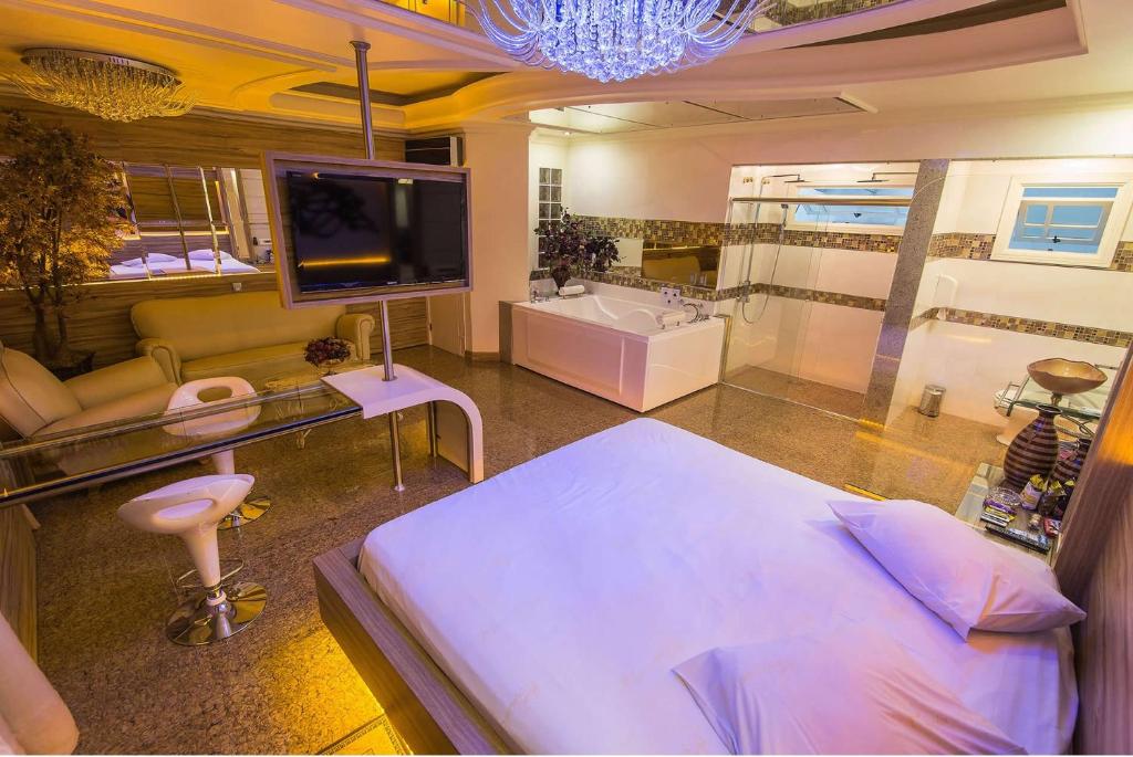 a bedroom with a bed and a tv and a bathroom at Golden Motel Diária suítes amplas, conforto premium e total privacidade in Passo Fundo