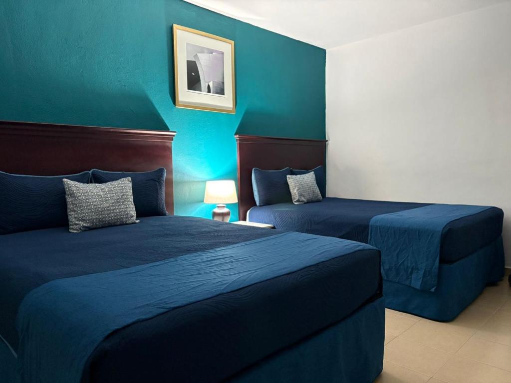 two beds in a room with blue walls at Hotel Palmeras Los Cabos in Cabo San Lucas