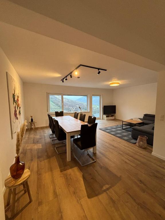 a dining room and living room with a table and chairs at Ferienhaus an der Burg Coraidelstein in Klotten