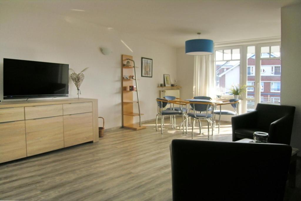a living room with a television and a table with chairs at Ferienwohnung De Dwarslöper in Dorum-Neufeld