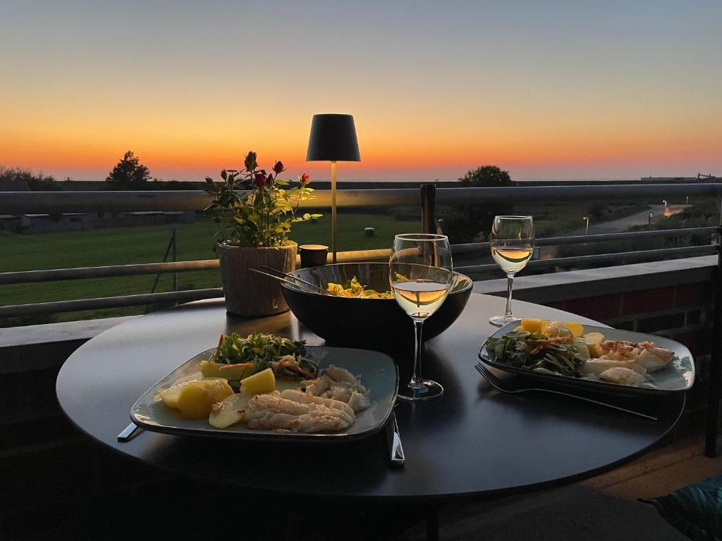 a table with two plates of food and glasses of wine at Ferienwohnung De Kraan in Dorum-Neufeld