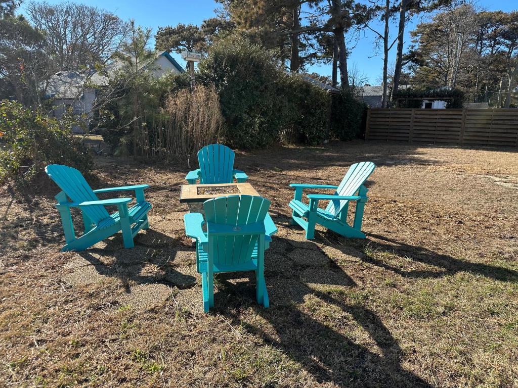 four blue chairs and a table in a yard at Shell'd Inn in Kill Devil Hills