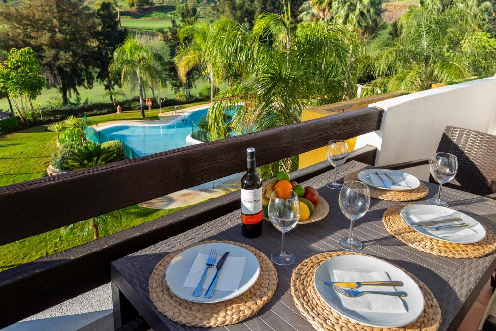 a table with plates of food and a bottle of wine at Modern Sea & Golf View 2-Bedroom Apartment with Pool and Terrace in Calanova in Mijas