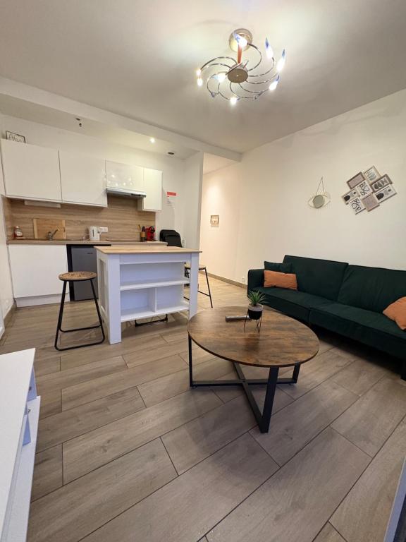 a living room with a green couch and a table at À quelques pas de la gare - RER A in Sartrouville