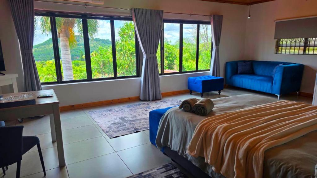 a bedroom with a bed and a chair and windows at Rosies on Robin - Pool, Braai & Mountain Views in Rustenburg