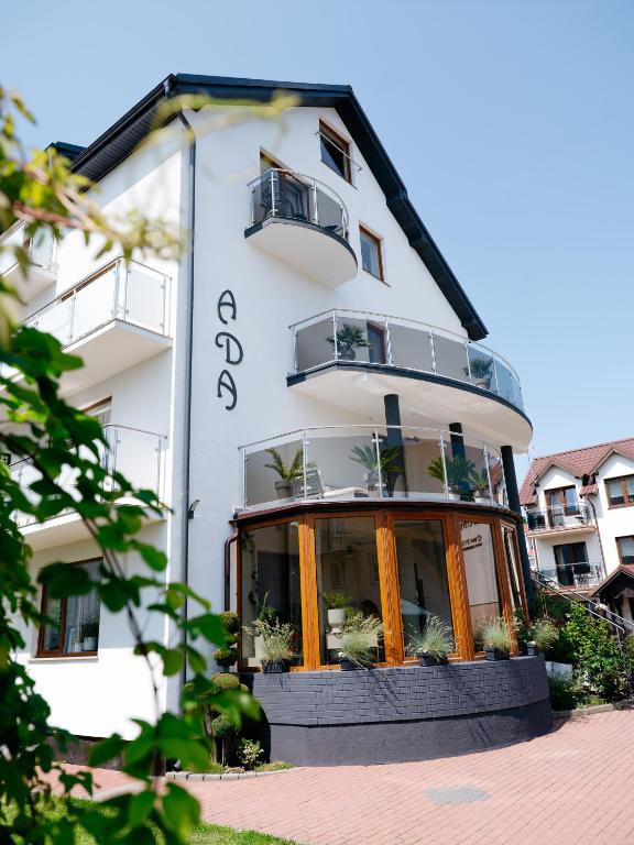 a large white building with a balcony at Willa Ada Pokoje & Apartamenty in Karwia