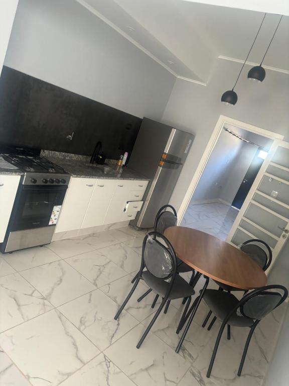 a kitchen with a table and two chairs and a stove at Hospedaje Adha Chivilcoy III in Chivilcoy