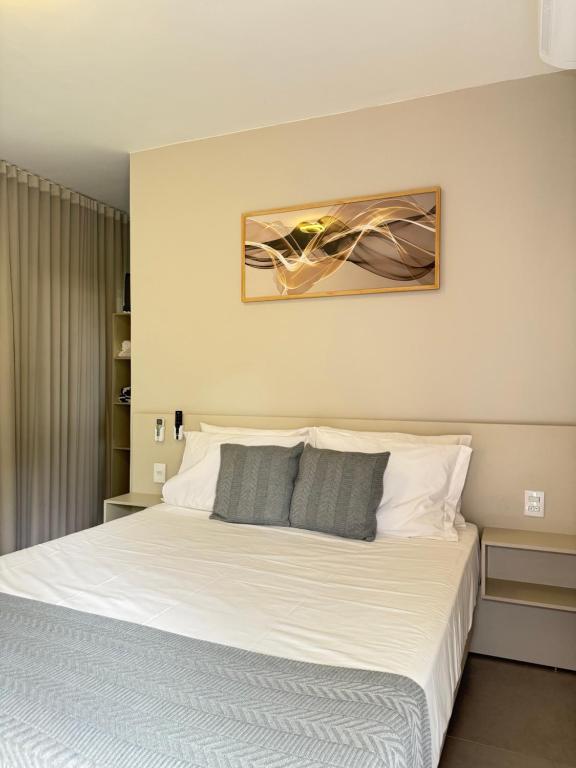 a bedroom with a large bed with white sheets at Pousada Vista do Voo in Brumadinho