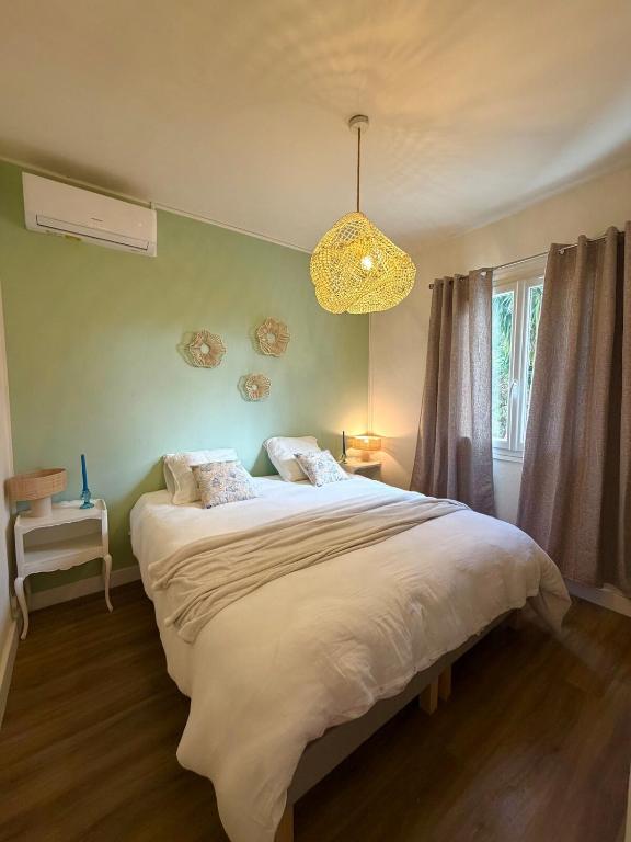a bedroom with a large bed and a chandelier at Villa San Michele 3 chambres in Linguizzetta