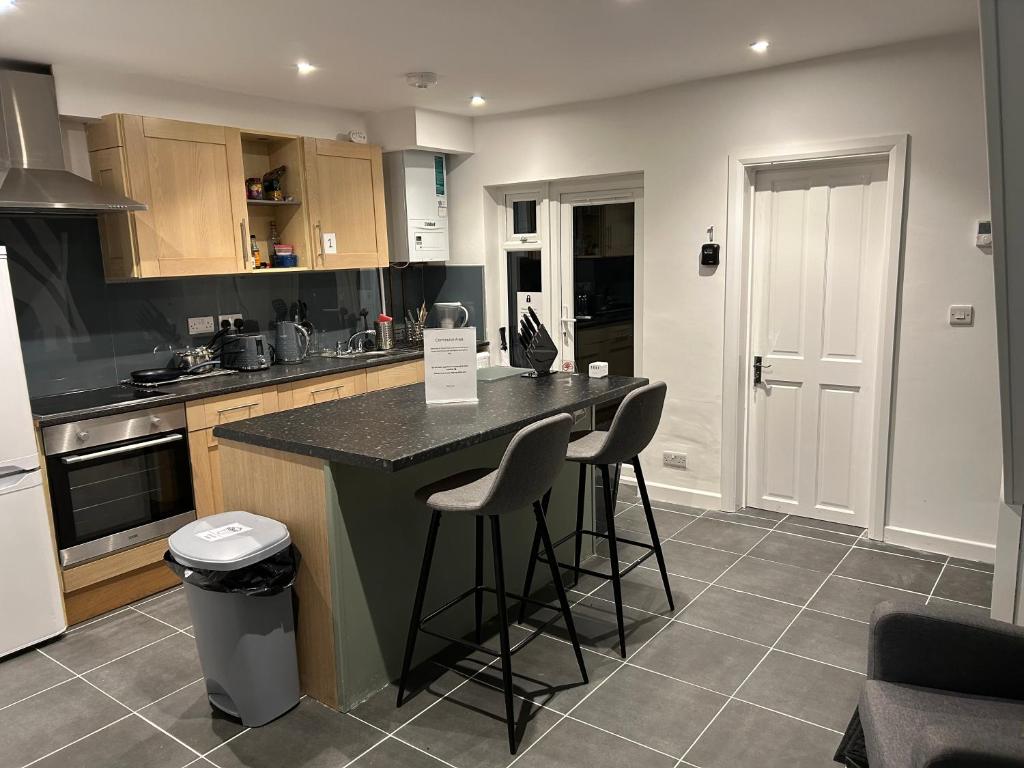 a kitchen with a counter and stools in it at The Grove En-Suite Rooms in Bristol