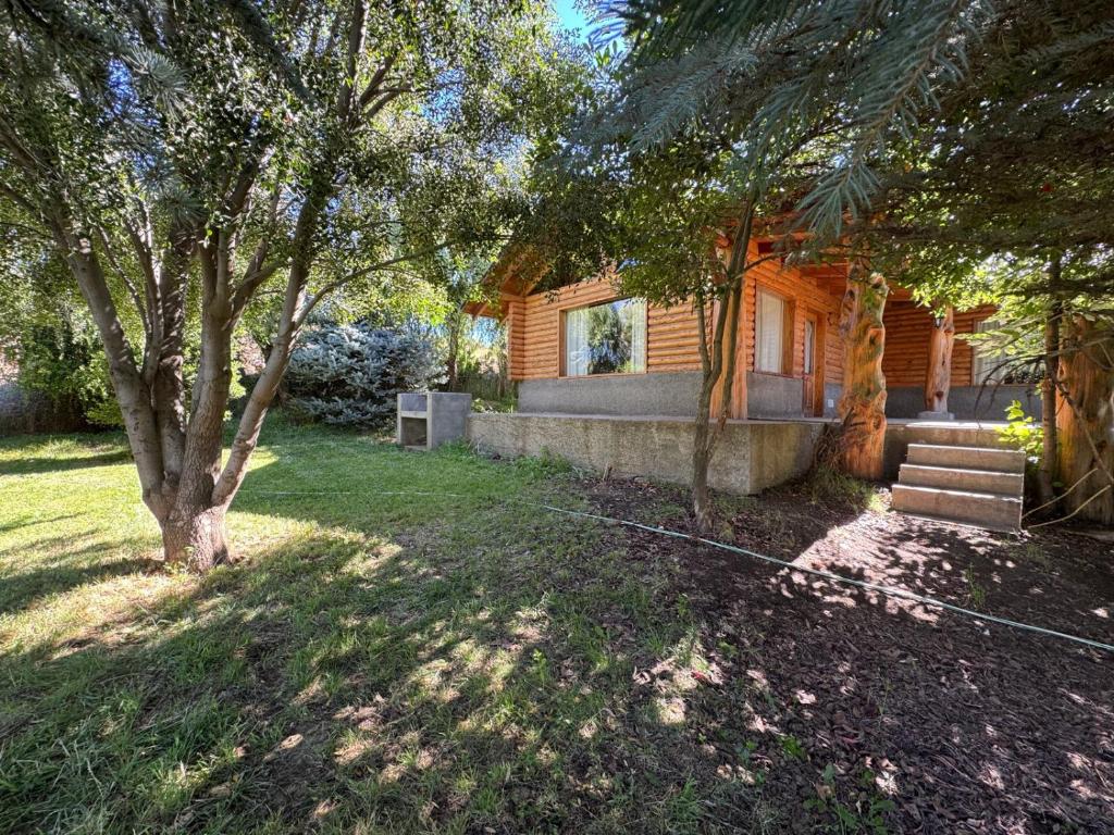 a house with a tree and stairs in the yard at Cabañas EL CAMPITO in Aluminé