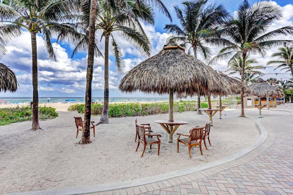 a beach with tables and chairs and palm trees at 2B Beachfront condo! Pool! Games! 15 mins to PBI! in Riviera Beach