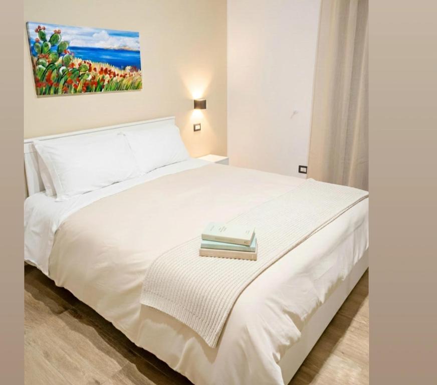 a bedroom with a white bed with a book on it at Etna Charme Guest House in Belpasso