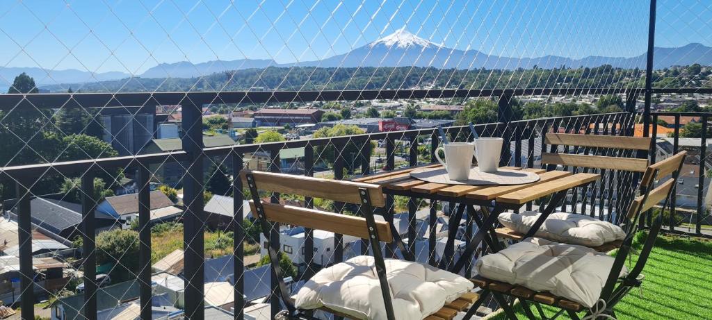 a table and chairs on a balcony with a mountain at Vista Insuperable in Villarrica