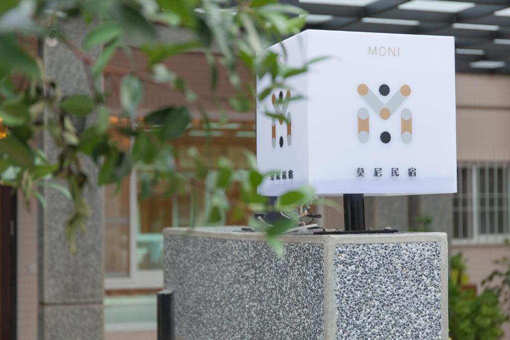 um sinal sentado em cima de um suporte ao lado de uma planta em Moni Bed Homestay em Taitung City