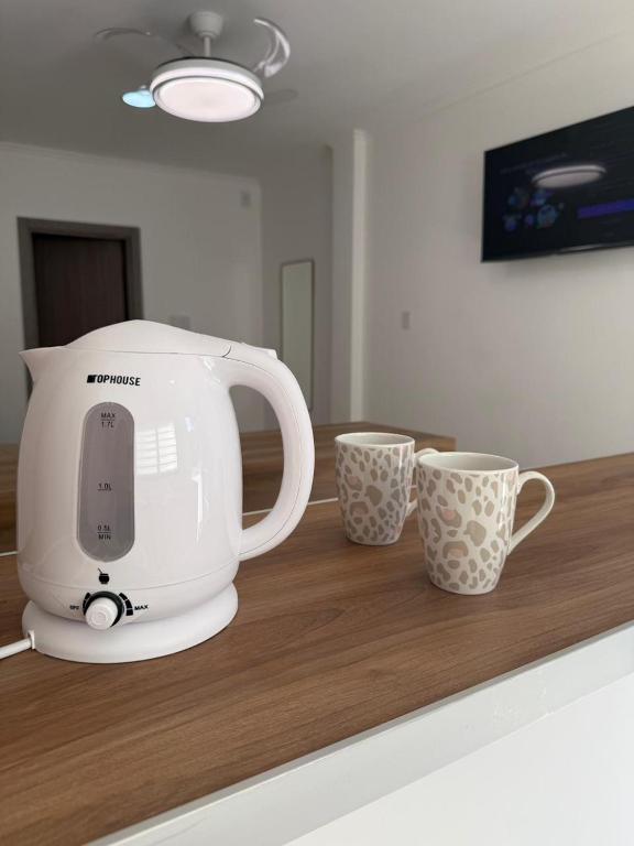 a white mixer sitting on a counter with two cups at Apart Continente Park in San Clemente del Tuyú