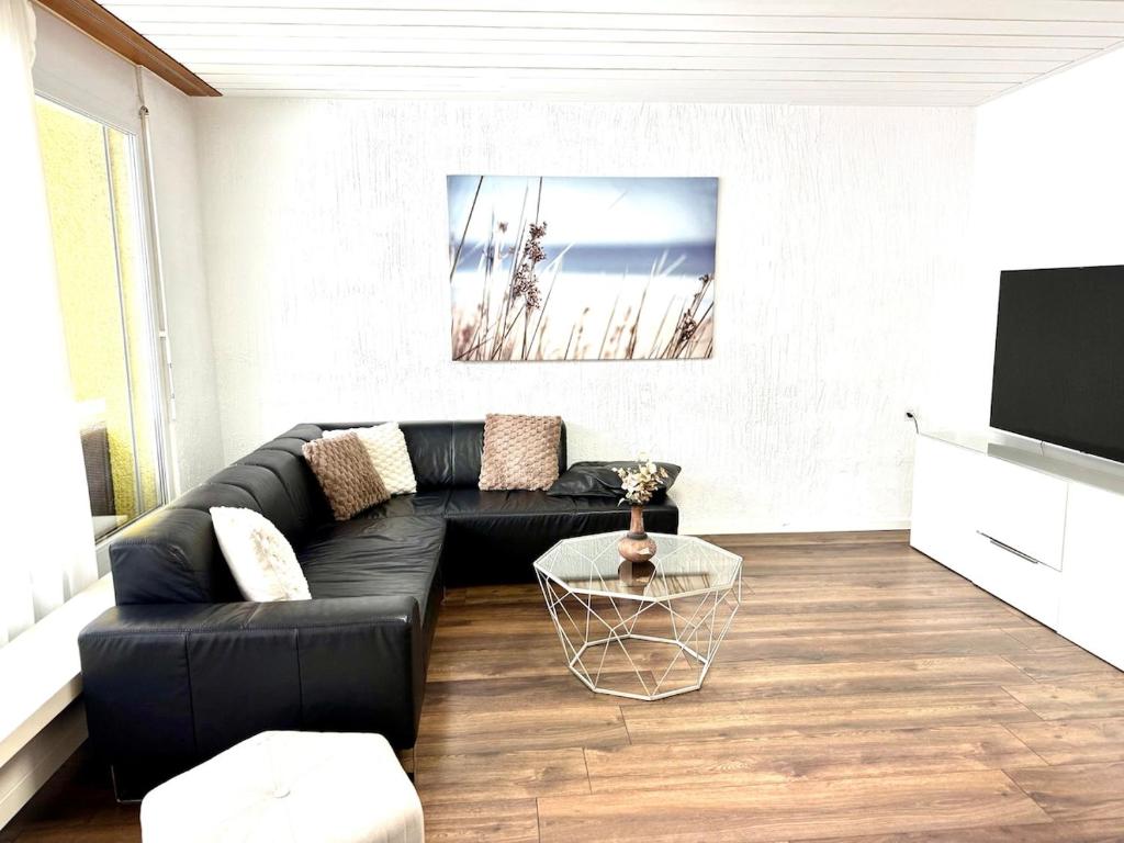 a living room with a black couch and a tv at Private 5 bedroom for large Groups in Hunzenschwil