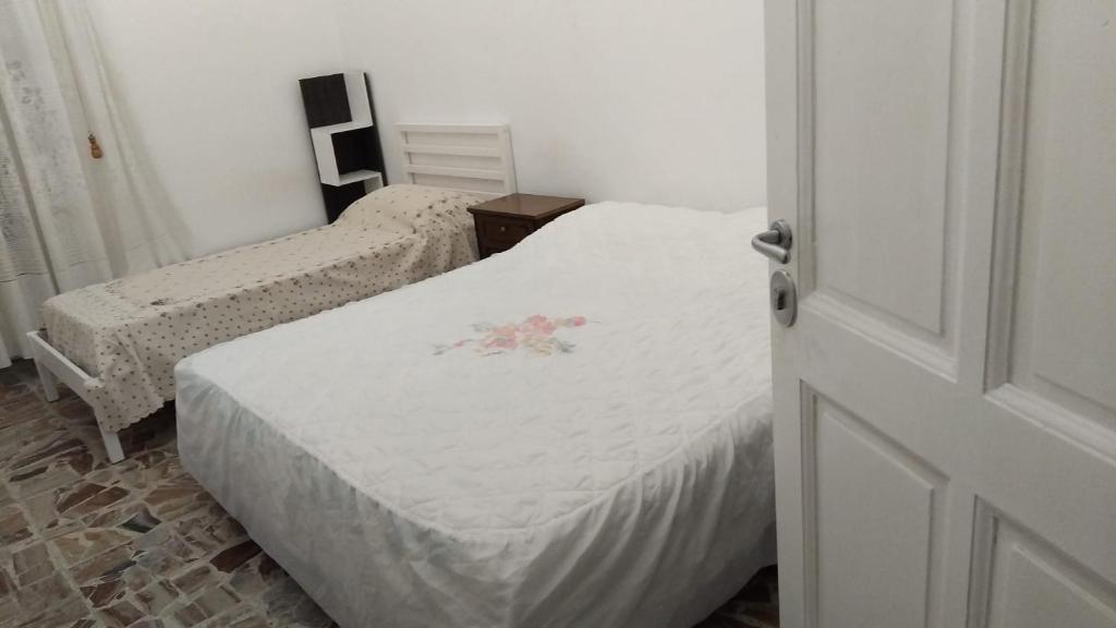 a bedroom with two beds with white sheets and a door at Le 3 Sirene in Bordighera