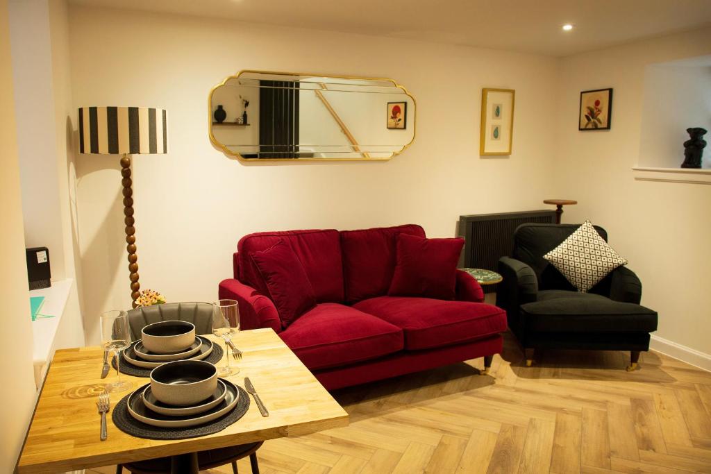a living room with a red couch and a table at Coorie-In Cottage in Whitehills
