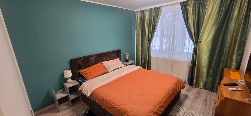 a bedroom with a bed with blue walls and a window at Apartament Central in Câmpina
