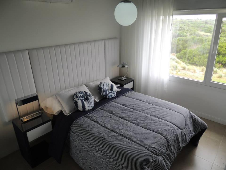 1 dormitorio con cama con almohadas y ventana en Linda Bay Playa en Mar de las Pampas