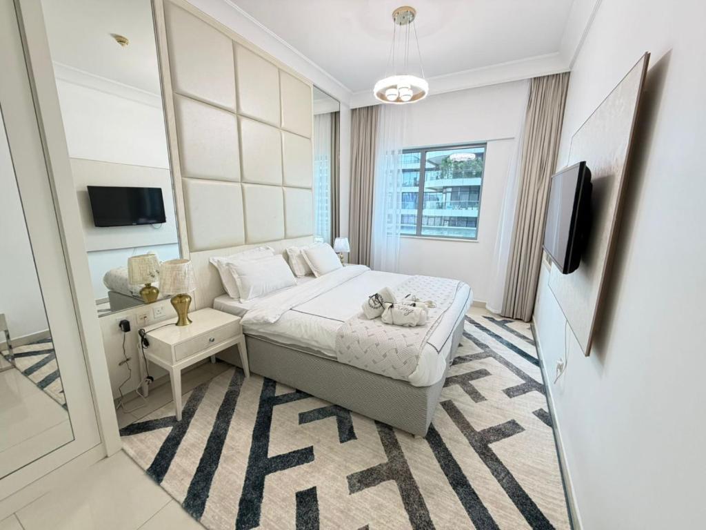 a white bedroom with a bed and a tv at Damac mall street in Dubai