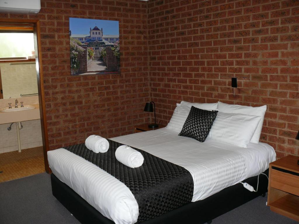 a bed in a room with a brick wall at Milawa Motel in Milawa