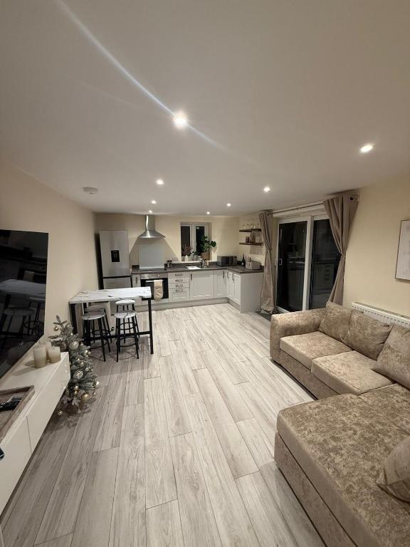 a large living room with a couch and a kitchen at New 2-bed 2-bath detached flat with garden in Enfield