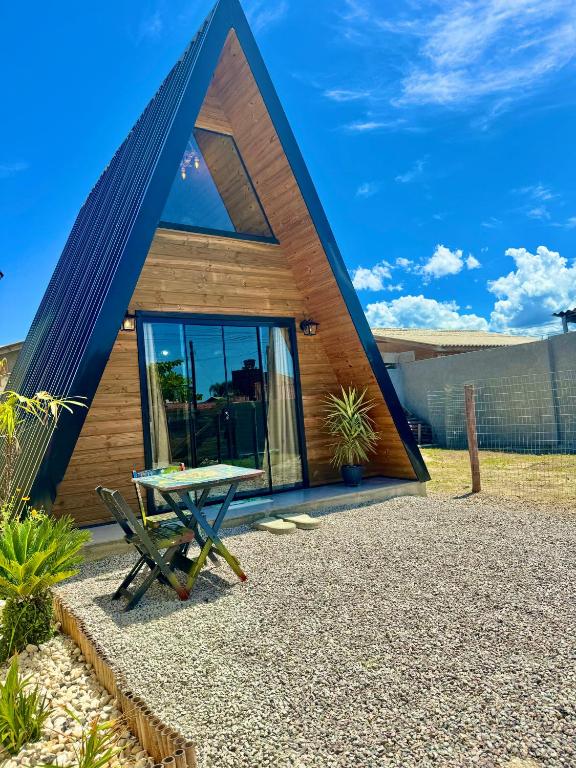 a house with a triangular roof with a picnic table in front at Chale do Boni in Palhoça