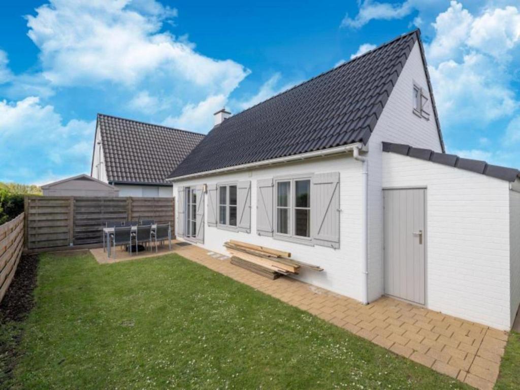 a white house with a bench in a yard at Nieuwendamme H114 in Lombardsijde