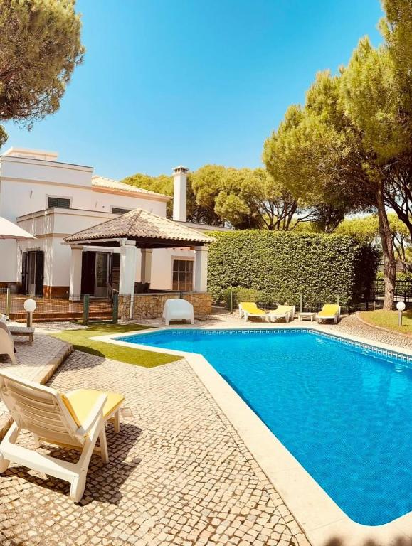 a swimming pool with chairs and a house at Coreto's Village in Praia Verde