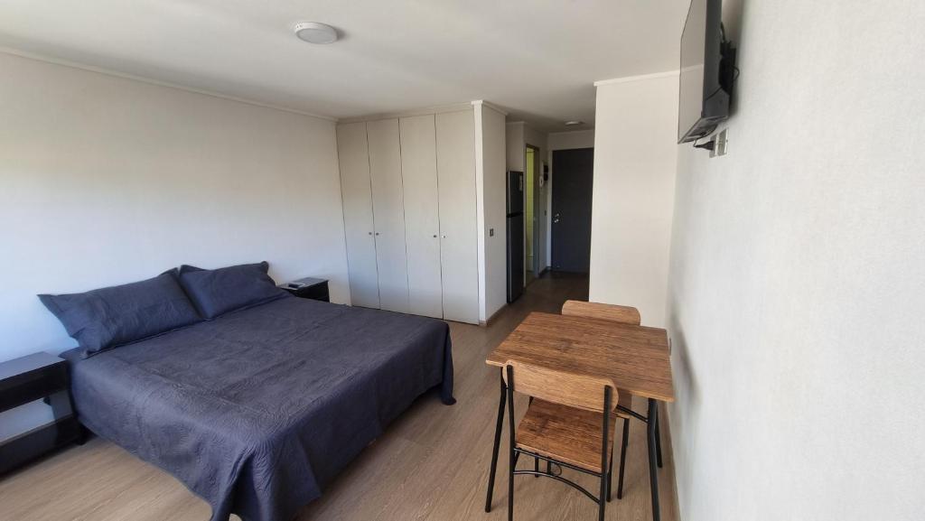 a small bedroom with a bed and a table at Departamento Studio en pleno centro de Concepción in Concepción