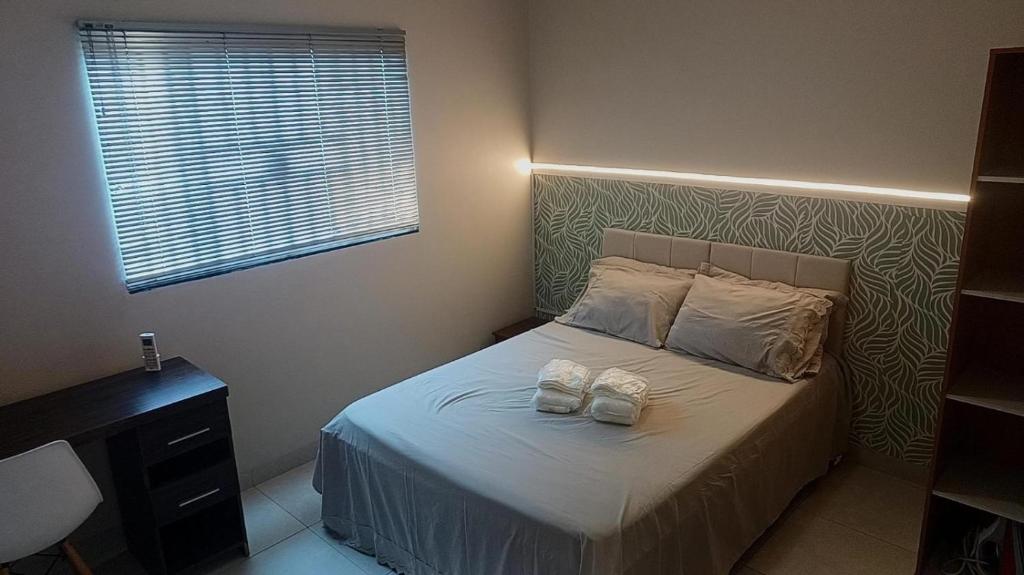 a bedroom with a bed with two shoes on it at Casa confortável com garagem coberta in Primavera do Leste