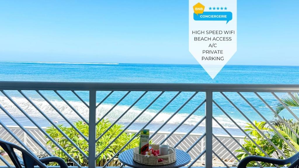 a table with a bottle of wine on a balcony overlooking the beach at Private beach access, fiber optic internet & parking in Punaauia