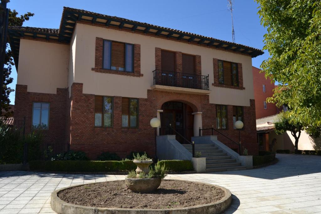 a large brick house with a fountain in front of it at Hotel Villegas in Valencia de Don Juan