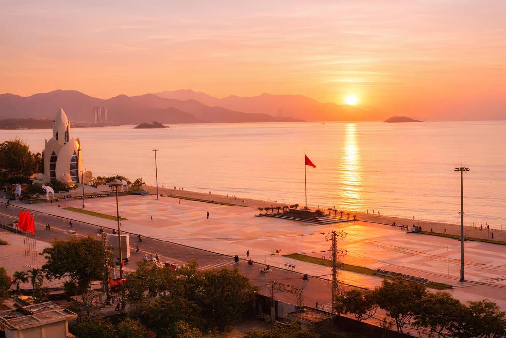 a sunset over a large body of water with a church at Sea Light Hotel Nha Trang Beach in Nha Trang