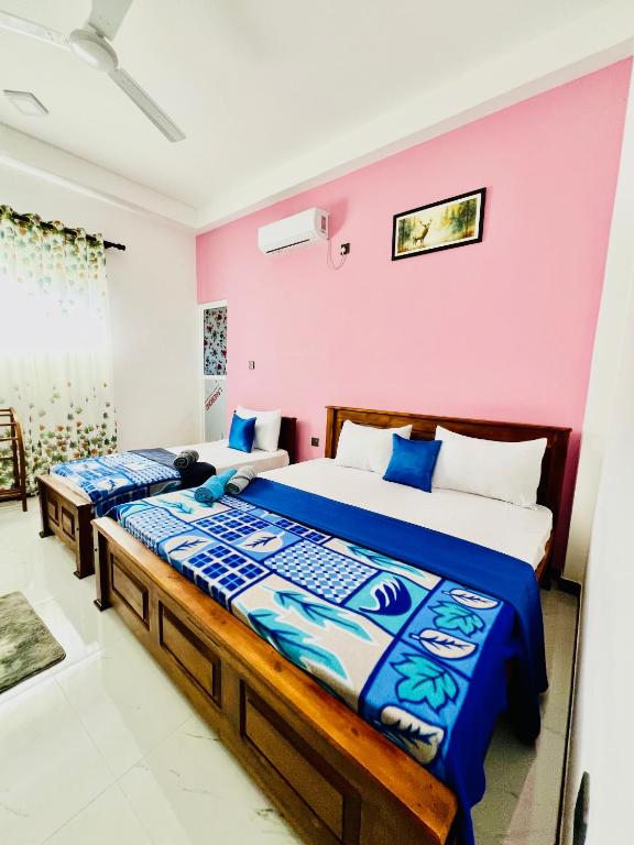 a bedroom with two beds and a pink wall at Messiah Royal Residence in Negombo