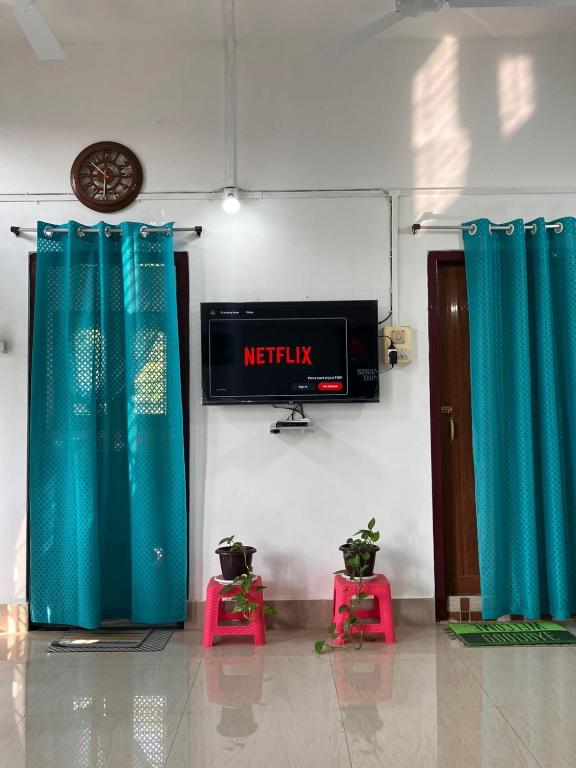 a room with blue drapes and a television and a clock at Green Stay , AC room in Sibsāgar