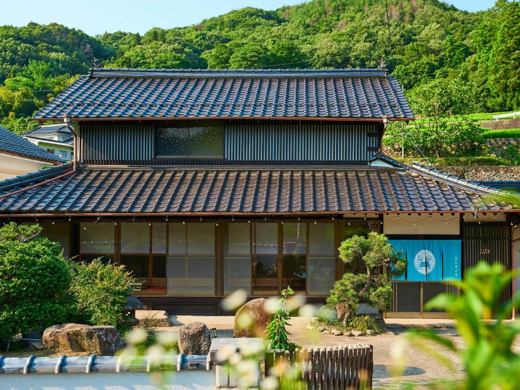 une maison asiatique avec une montagne en arrière-plan dans l'établissement villa Like hiroshima 愛犬と泊まれる一棟貸し, à Mihara
