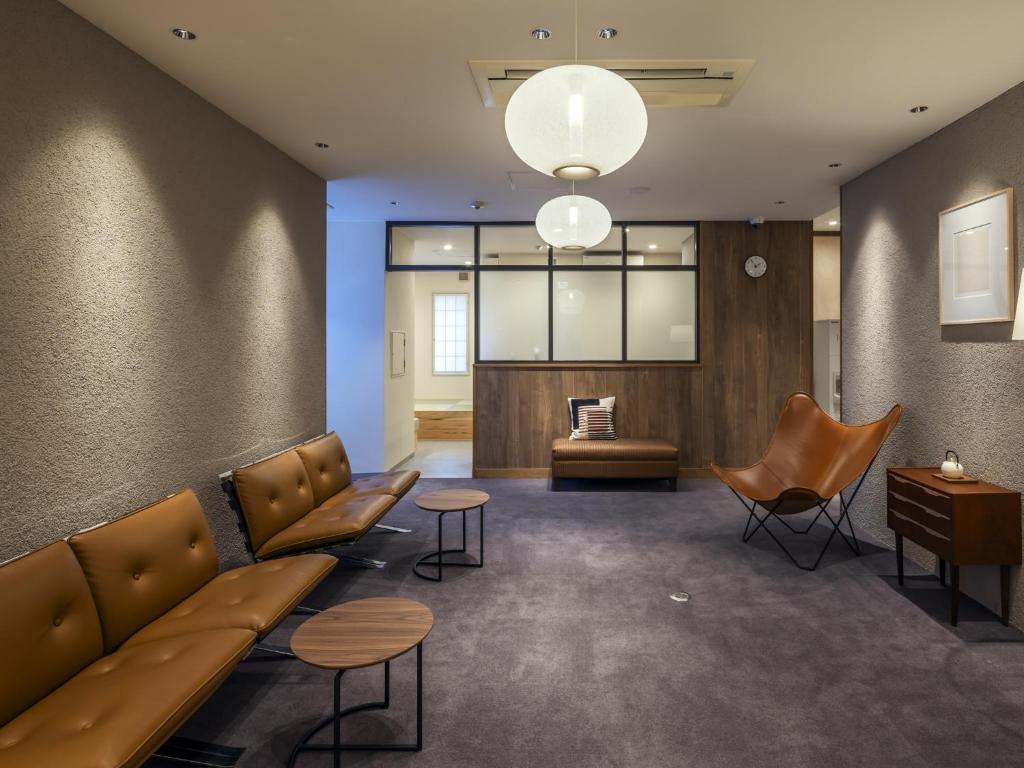 a waiting room with leather couches and chairs at Apartment Hotel DIG the OSAKA in Suita
