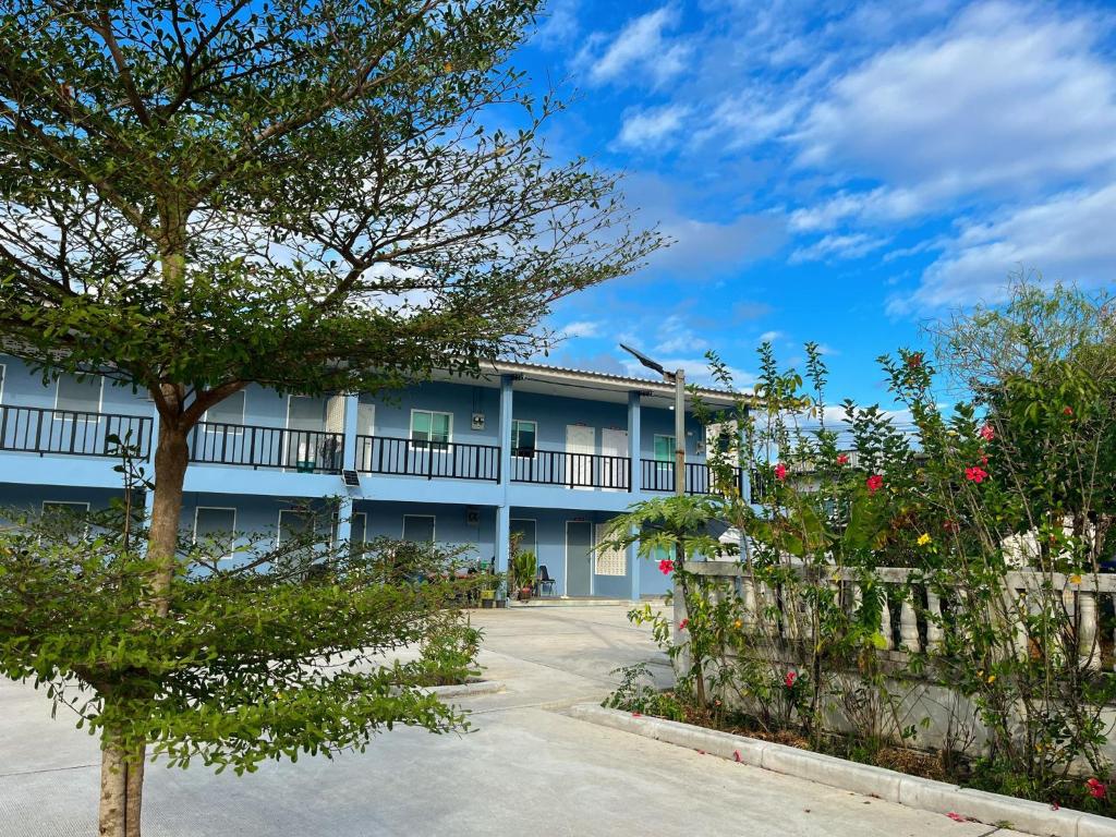 a apartment building with a fence and a tree at Wanderlust Homestay Ranong in Ranong