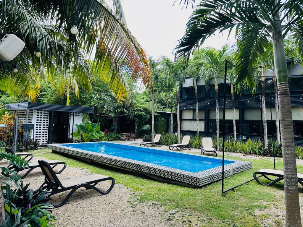 a swimming pool in a yard with chairs and a building at Bacalar 102 Hotel in Bacalar