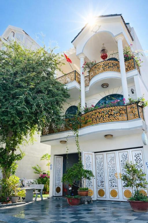 a white building with a balcony with plants on it at Lộc Vừng Homestay in Phan Thiet