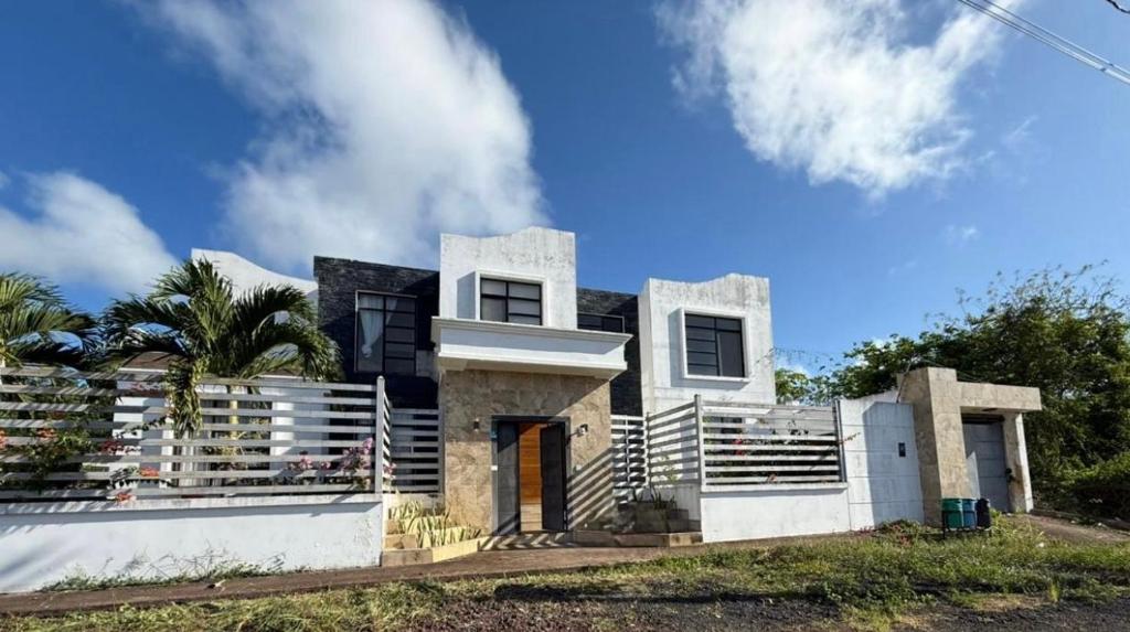 a white house with a palm tree in front of it at Enchanted Haven in Puerto Baquerizo Moreno