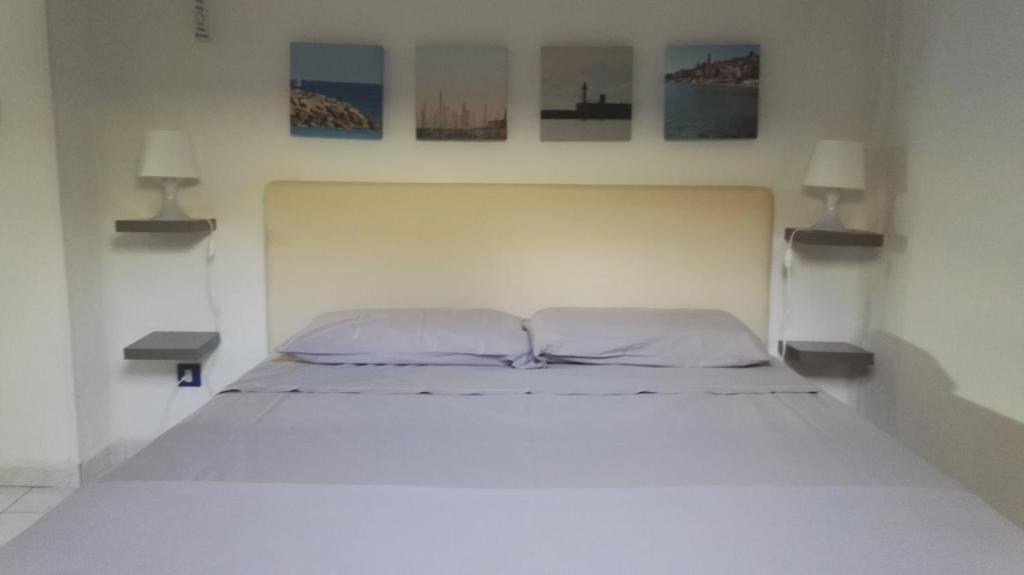 a white bed in a bedroom with two lamps at Pied-a-terre Saint Michel in Menton