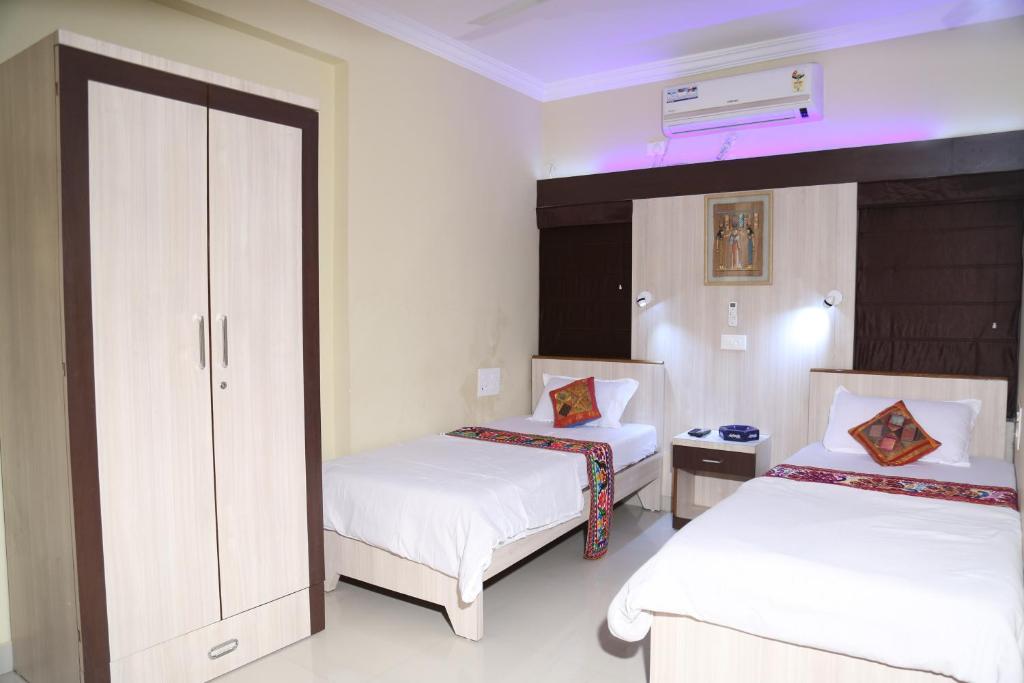 那格浦爾的住宿－Shivam Apartment，一间卧室配有两张带白色床单的床和橱柜