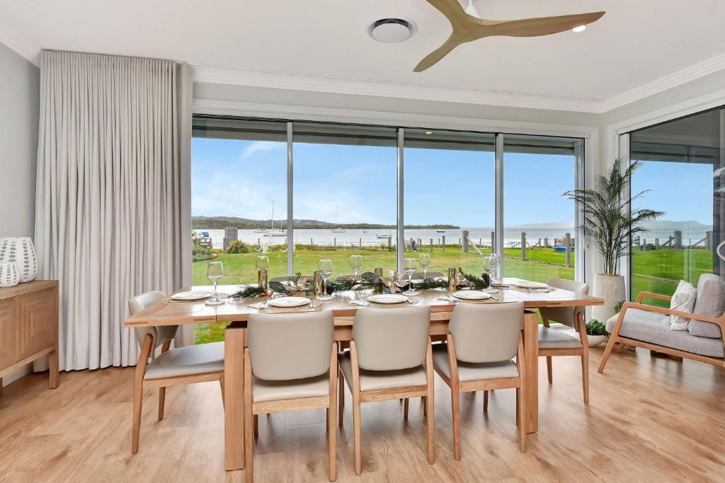 a dining room with a table and chairs and a large window at Tilligerry Beach Retreat in Taylors Beach